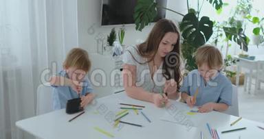 两个<strong>男孩</strong>的孩子和他的母亲坐在厨房里<strong>画画</strong>。 家庭幸福。 兄弟们在桌子旁<strong>画画</strong>。 实际